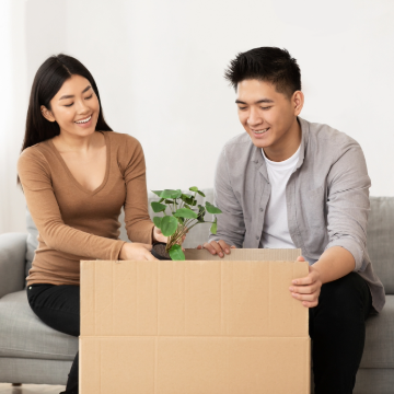 Happy man and woman unpacking moving box